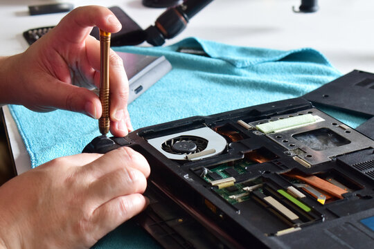 Computer repair technician, laptop motherboard repair technician uses a screwdriver to disassemble computer components to remove them for replacement and repair.