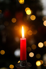 Burning christmas candle on background christmas tree with golden lights bokeh. Merry Christmas and Happy Holidays! Christmas advent, holiday candlelight background