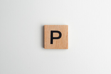 Wooden alphabet block with the letter "P" on a white isolated background, flatlay style with copy space. Educational wooden toy for children or creative design projects.