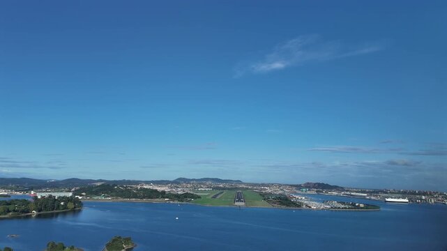 An immersive pilot&rsquo;s eye from the cockpit of a jet airplane approaching to Santander airport, overflying the bay, with a far view of the city, under a blue sky with few clouds.