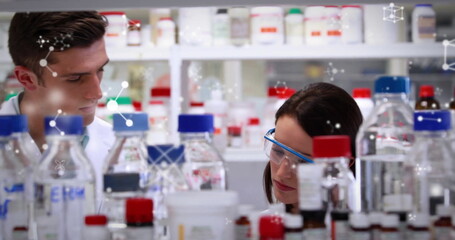 Male and female scientists in lab coats handling reagent bottles at bench, with molecular graphics