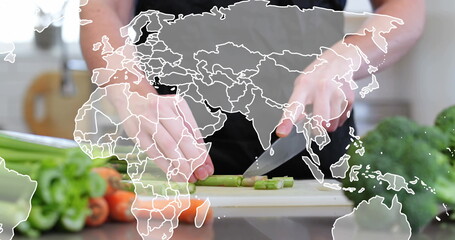 Slicing adult hands wearing dark apron chopping asparagus on cutting board, with world map overlay