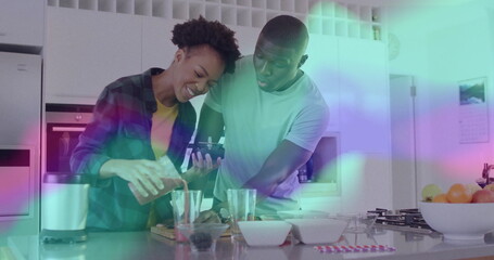 Pouring orange juice cooking couple preparing drink behind kitchen island, with phone and blender