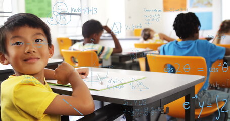 Boy in yellow Tshirt leaning on desk in classroom with translucent math overlay, copy space