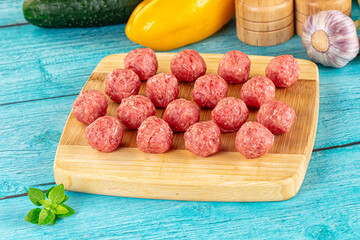 Raw beef meatballs over board