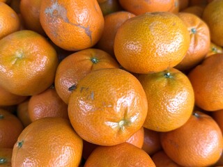 Pile of fresh mandarin oranges displaying their vibrant color and one of them has a fly