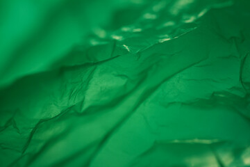Extreme close up of green empty plastic bag background. The plastic surface is wrinkly and tattered...