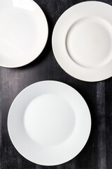 Big white plates on black chalkboard background. Flat lay. Top view. Food concept. Dark mood food photography.