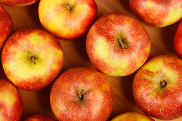 An overhead view of a grid of red and green apples, neatly arranged in rows on a wooden surface