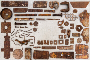 A group of various old rusty bits and pieces arranged on a concrete surface. Old rusty nuts, bolts,...