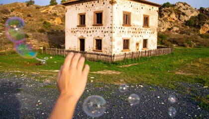 Child's Hand Reaching for Rainbow Soap Bubbles Near Abandoned House
