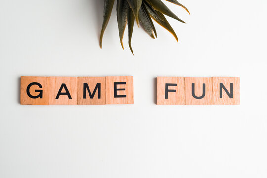 Wooden tiles with the letters "Game Fun" on a white background. The word "Game Fun" is written on a wooden piece or wooden cube.