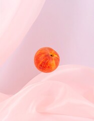 A peach floats amidst pale pink fabric