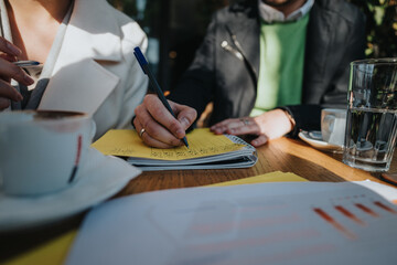 Business people discuss ideas and strategies while taking notes in a relaxed outdoor setting, fostering creativity and teamwork.