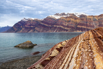 Looking along the dramatic and colourful rock formations of Eleonore Bay, Segelsallskapet Fjord, Northeast Greenland National Park. Alternating layers of limestone and dolomite deposits are visible.