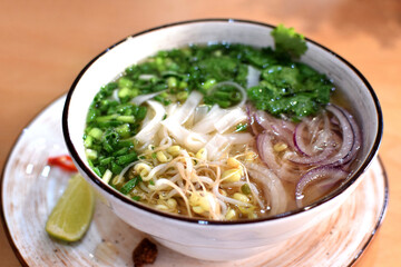 Pho Bo soup with beef, rice noodles, ginger, lime and chili pepper in a bowl. Vietnamese cuisine.