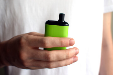 One electronic cigarette in the hand of a teenager. Vaping with nicotine. Danger for teenagers.