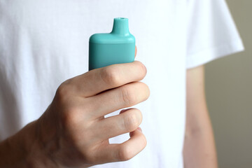 One electronic cigarette in the hand of a teenager. Vaping with nicotine. Danger for teenagers.