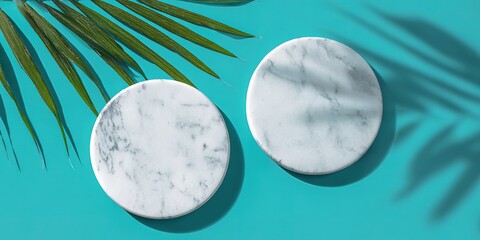 Two white marble round coasters on a turquoise background with the shadow of a palm leaf, a flat lay top view with copy space.
