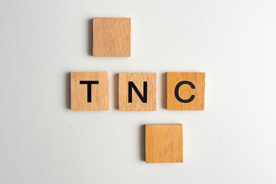Wooden block tiles with the letters "TNC" on a white background. The word "TNC" is written on a wooden piece or wooden cube.