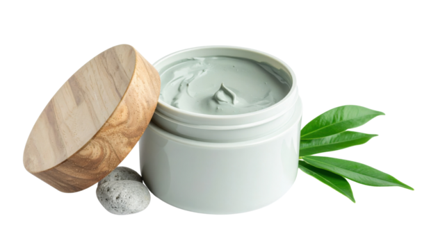 A white jar of pale green clay facial mask with a wooden lid, a smooth stone, and fresh green leaves.