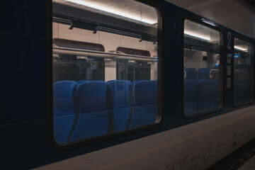 View through the train window showing empty blue seats in a second-class carriage at night in Serbia