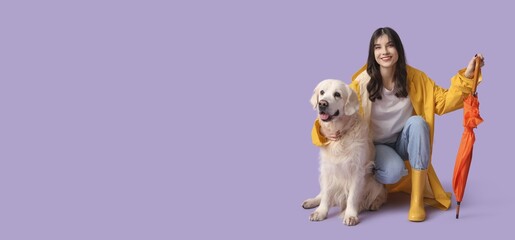Young woman in raincoat with umbrella and cute dog on lilac background with space for text