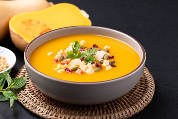 Butternut squash pumpkin soup in a bowl on black background, Homemade food in autumn season