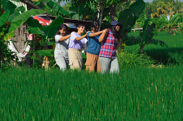 Four cheerful girls walk in a playful line, holding each otherâ€™s shoulders as they leave the...
