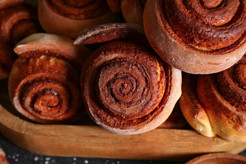 Wooden tray with tasty cinnamon rolls on table