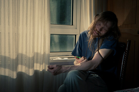 The High and The Low. A drug user injecting himself in a darkened room. The image evokes feelings of addiction, drug abuse, and dependence.