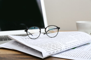 Newspapers with glasses on wooden table