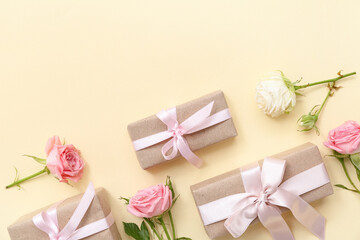 Elegant wrapped gift boxes and rose flowers on beige background