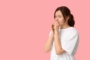 Religious young woman praying on pink background