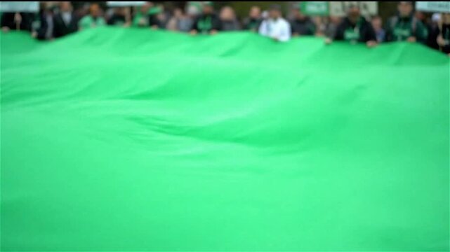 People Holding a Large Green Fabric Sheet Outdoors