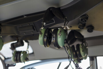 Headsets hang in the cockpit, ready for use during helicopter operations. The environment is...