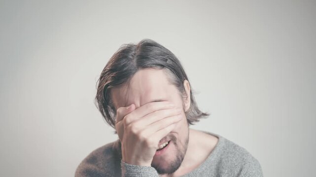 facepalm Young white man with blue eyes shows a facepalm gesture while laughing, expressing frustration and humor in an intimate setting