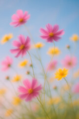 Soft-focus image of blooming pink and yellow wildflowers against a blue sky, evoking a dreamy and ethereal springtime atmosphere