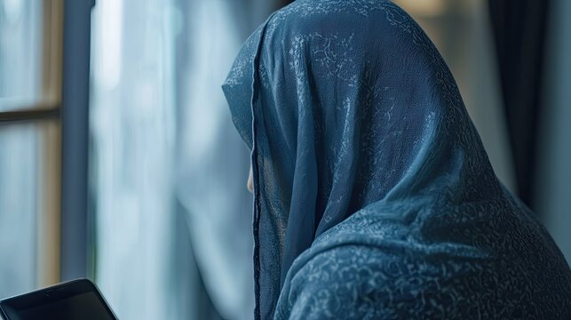 Woman in hijab using tablet with indoors.