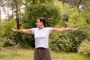 Woman doing stretching exercises on mat in the park. Fitness and wellness. Outdoor exercise....