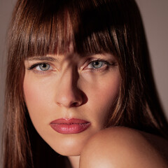 Close up female face with intense gaze and natural makeup in strong light and shadow contrast....