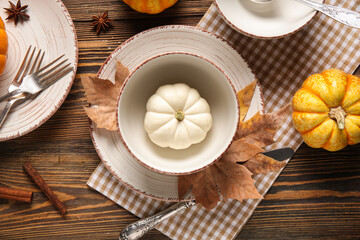 Beautiful table setting with fresh pumpkins, star anise, cinnamon and autumn leaves on wooden...