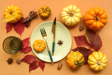 Beautiful table setting with fresh pumpkins, acorns, star anise, cinnamon and autumn leaves on orange background
