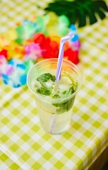mojito in a plastic glass with a straw on festive table
