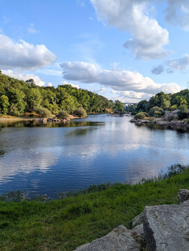 Sky and clouds reflecting onto river surrounded by trees