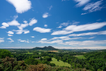 Fototapeta premium Scenic landscape of the Eildon Hills seen from Walter Scott’s View, overlooking rolling farmland, woodland and open countryside under a bright summer sky with scattered clouds