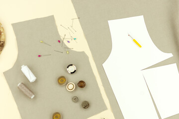 Sewing clothes using patterns. Modeling a dress. Fabric, pattern, sewing accessories on a beige background.