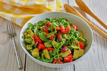 mixed green salad topped with cucumber, avocado, and tomato