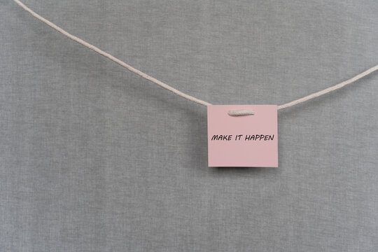 Pink note hanging on the rope with the inscription make it happen