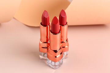 Beautiful red lipsticks on beige background, closeup